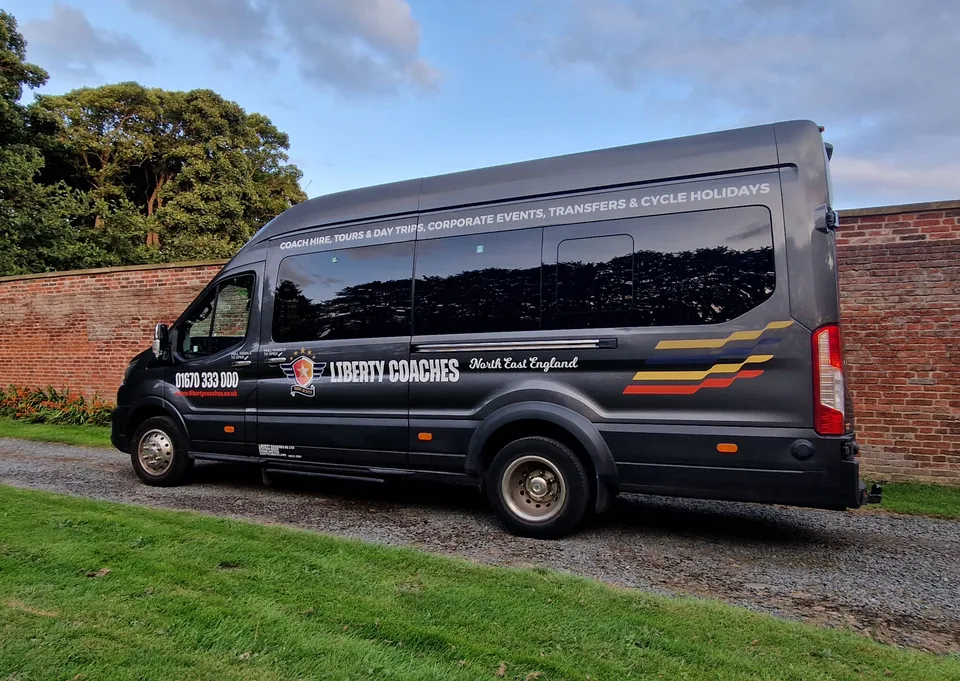 Dark Liberty Coaches minibus parked beside a brick wall