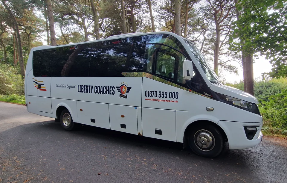 Light Liberty Coaches minibus on a tree-lined road